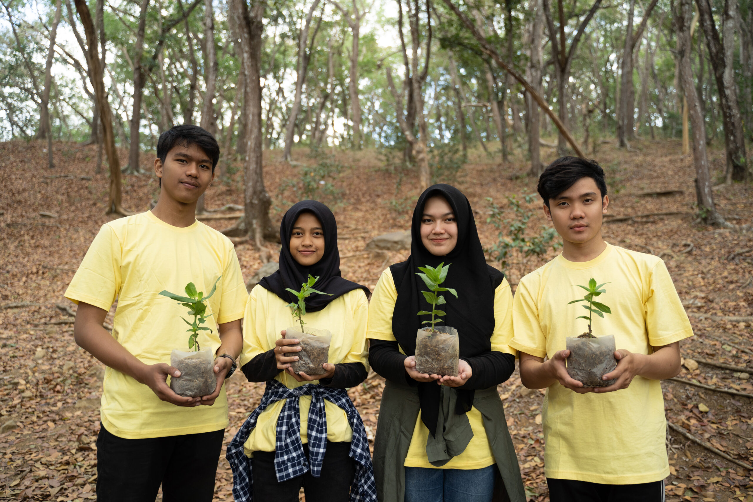 Young friends with new trees volunteering in park